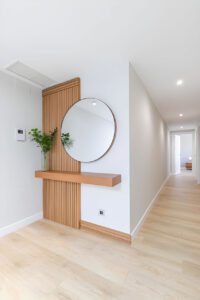 Hall De Entrada Com Painel Ripado De Madeira Bege Com Aparador Flutuante E Espelho Redondo E Moldura Madeira